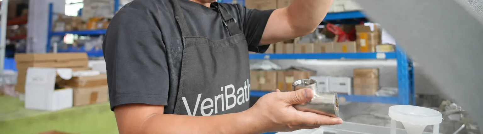 VeriBath staff member checking a stainless steel fitting at the leak test tank
